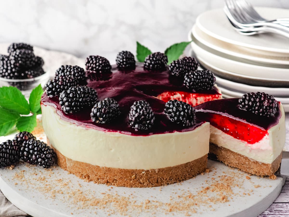 Taking a slice out of a cheesecake with blackberry coulis topping.