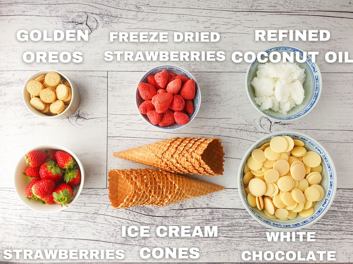 Ingredients for strawberry crunch cones: golden Oreos, freeze dried strawberries, refined coconut oi, fresh strawberries, ice cream cones, white chocolate.