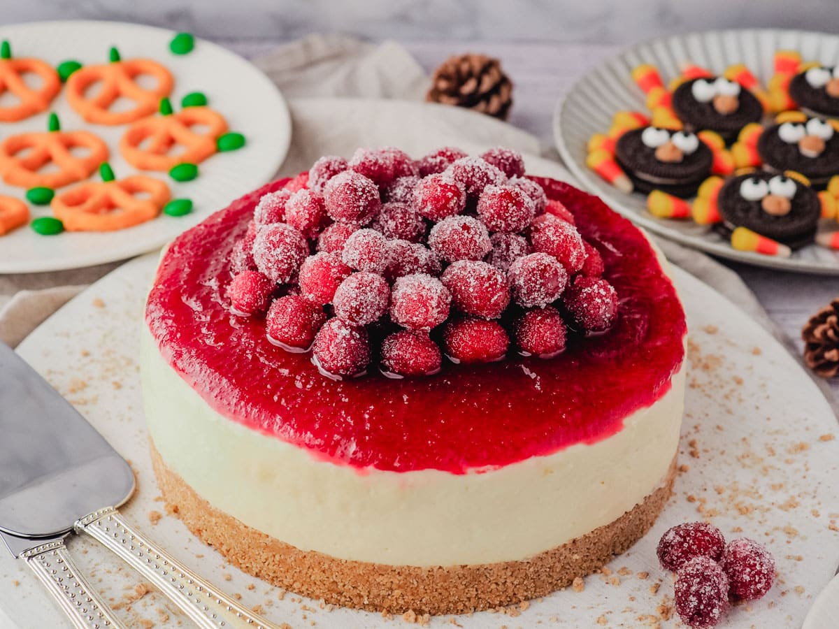Sugared Cranberries 6 Sugared cranberries piled on top of a cranberry cheesecake with cranberry sauce, on a Thanksgiving dessert table.