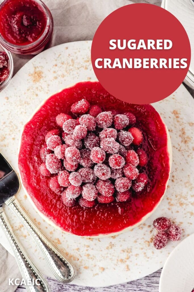 Serving sugared cranberries piled on top of a cranberry cheesecake with cranberry sauce, with serving wear on the side, with text overlay.