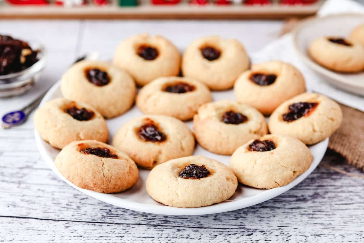 Mincemeat Thumbprint Cookies 7 A plate of mincemeat thumbprints with a small bowl of fruit mince and spoon in the background.