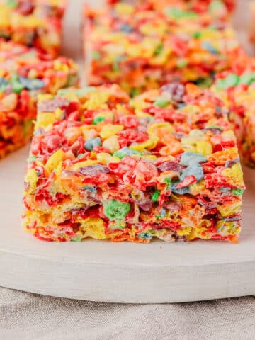 Close up view of a Rice Krispies treat with Fruity Pebbles on a serving board.