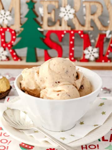 Scoops of Nini Creami Christmas ice cream in a bowl with a spoon on the side and Christmas decorations in the background