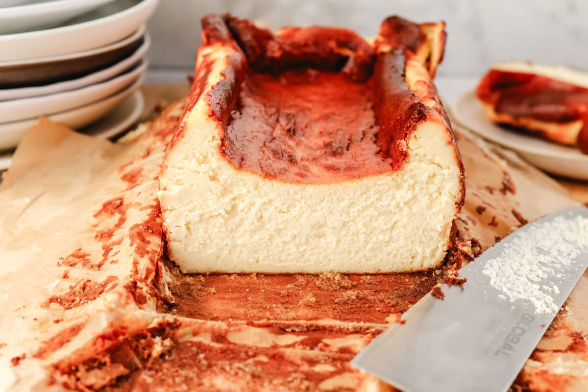 Side end view of a loaf pan Basque cheesecake with a slice taken off the end.