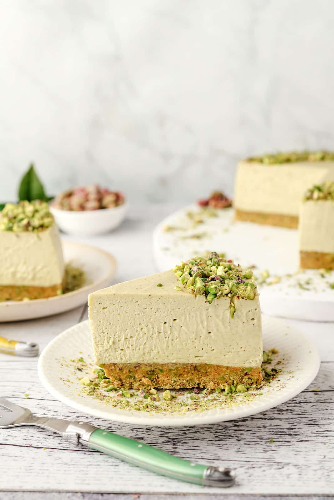 Slice of pistachio nut cheesecake decorated with pistachio crumbs.
