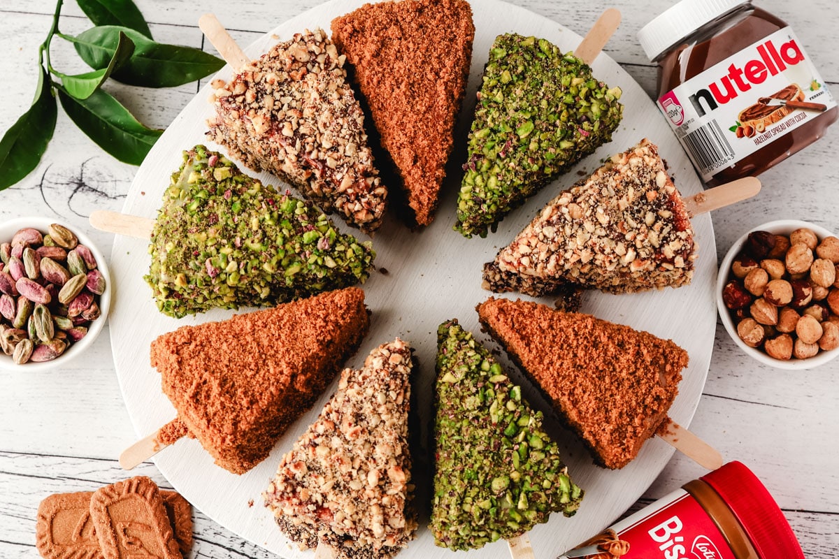 Cheesecake Sticks 18 Biscoff, pistachio and Nutella cheesecake sticks arranged in a circle on a serving board.