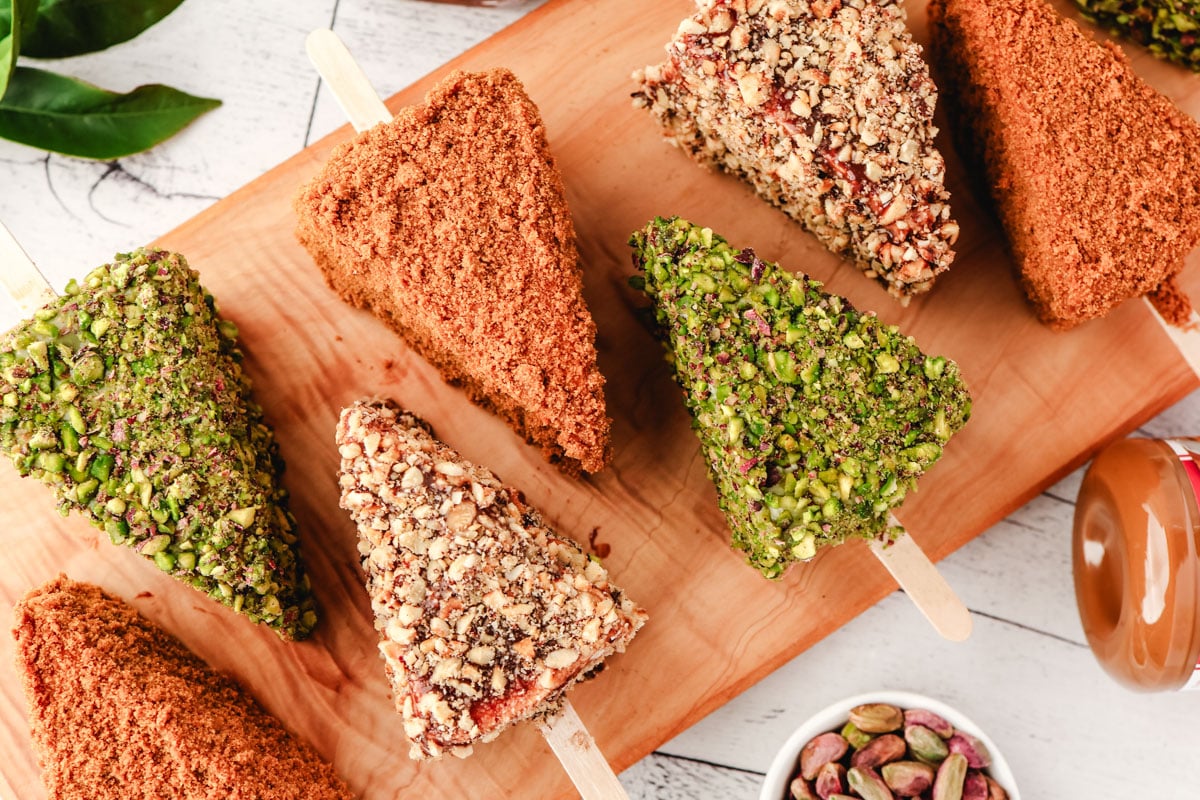 Cheesecake Sticks 2 Biscoff, pistachio and Nutella cheesecake sticks on a serving board.