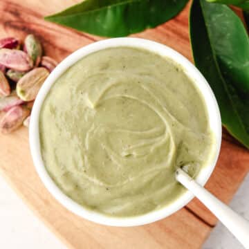 Top down shot of pistachio topping in a serving bowl, with a spoon on the side.