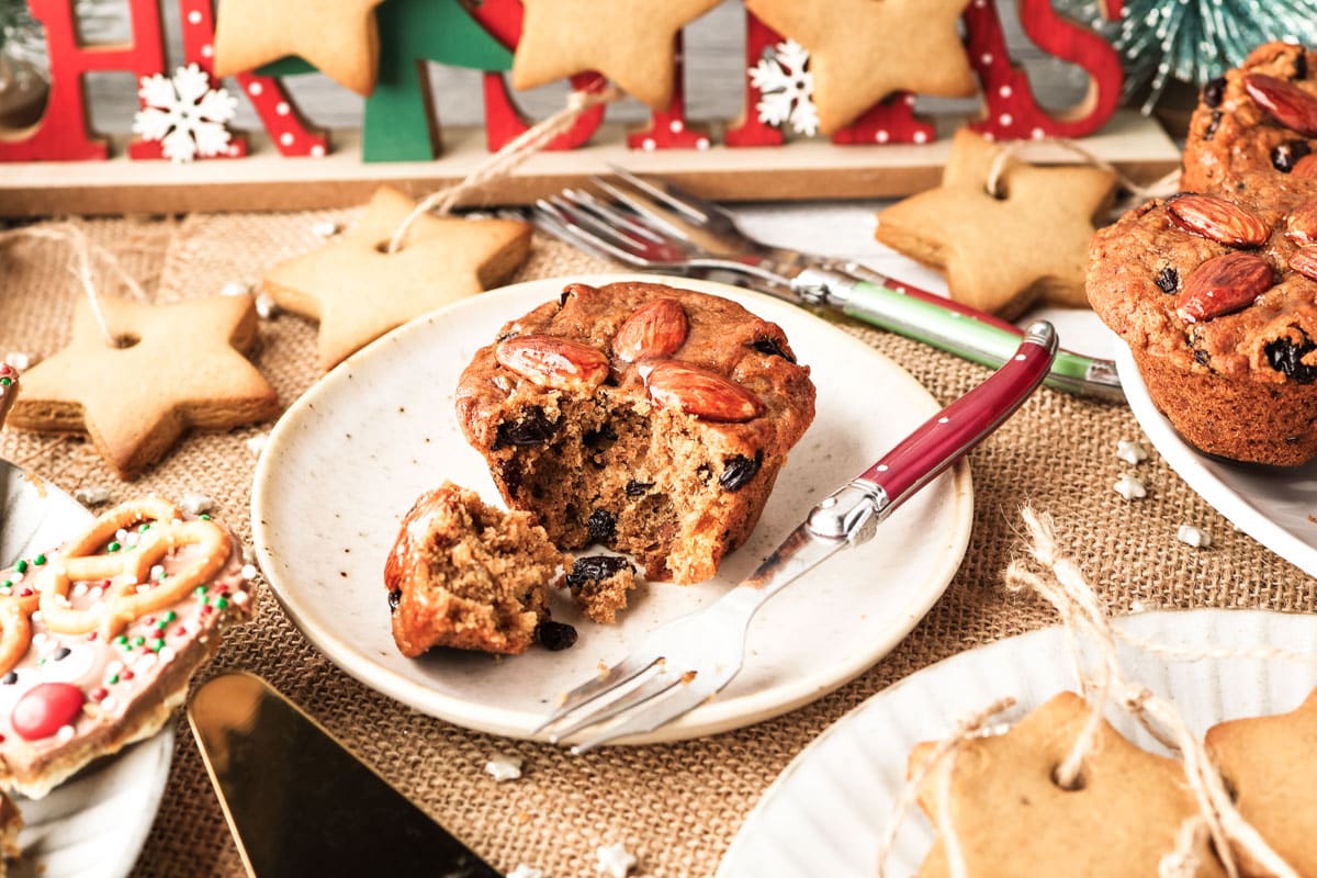 A mini Christmas cake on a plate with a fork full taken our, showing the cake and dried fruit inside.