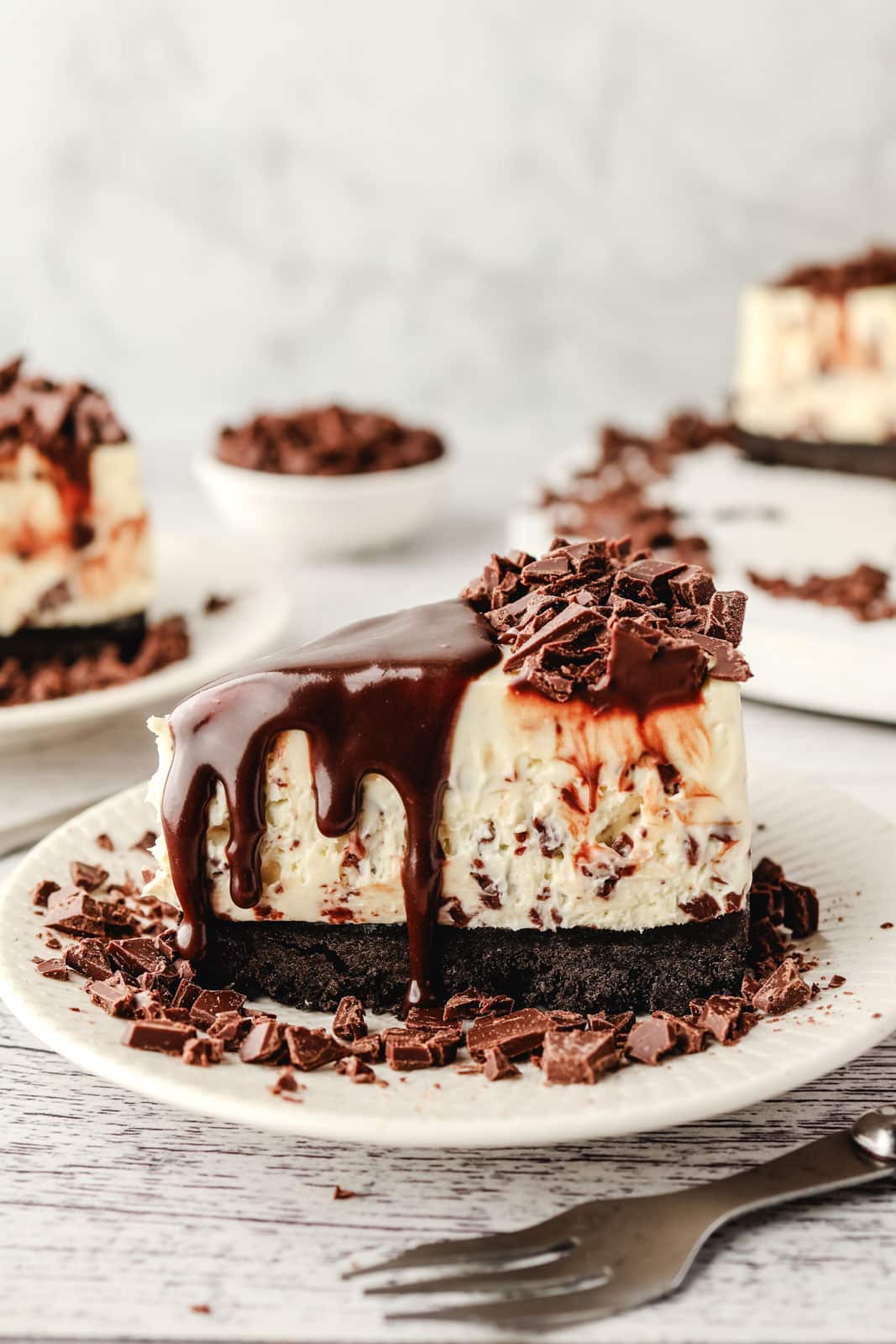 Chocolate Chip Cheesecake 9 Slice of chocolate chip cheesecake with a chocolate cookie crust drizzled in homemade chocolate sauce, with a bowl of chocolate chips and the remaining cheesecake behind it.